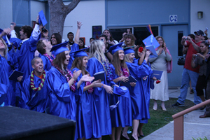 Students in graduation gowns cheering